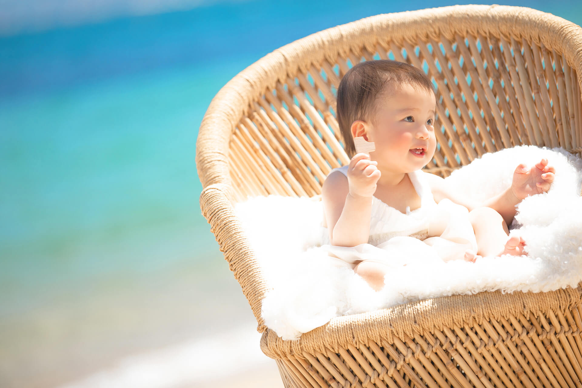 海を背景に椅子に座り笑う赤ちゃんの撮影風景